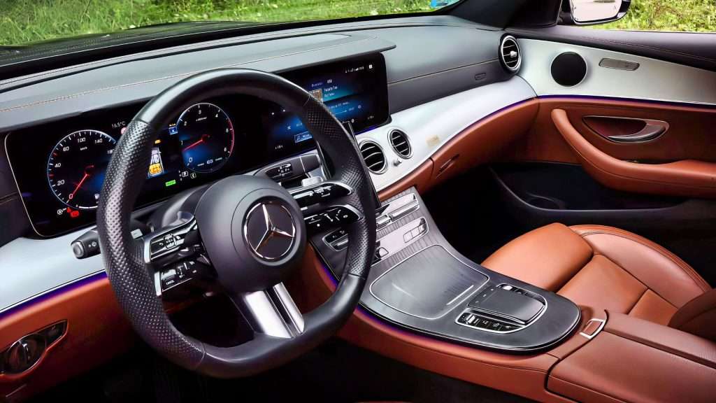 VTC Elvis El interior de este vehículo VTC en Cantabria presenta un elegante volante, tablero de instrumentos digital y asientos de cuero marrón con elementos de diseño moderno, personificando el lujo y la comodidad. servicios de VTC en Cantabria